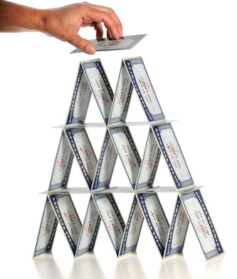 Man's hand building house of cards with social security cards isolated over white background - Dealing With Reality – There Is No “Security” In Social “Security” - Miller on the Money