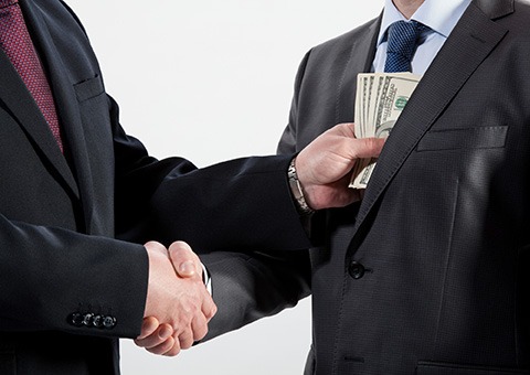 Corrupt businessmen shaking hands while exchanging bribe - corrupt - You’re Buying the Government? - Miller on the Money